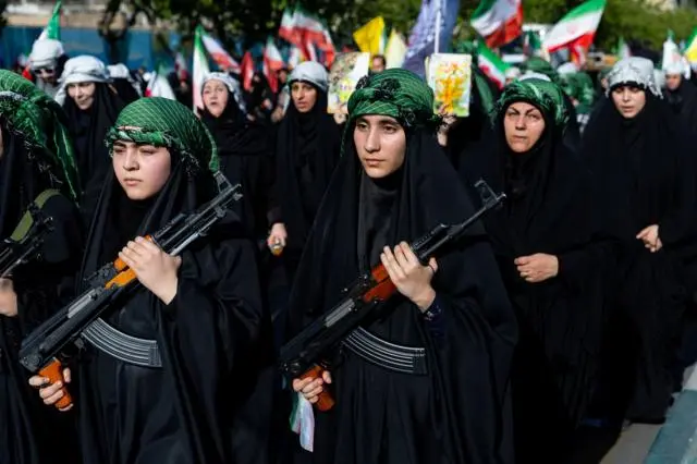 عضوات في قوات الباسيج يحملن أسلحة خلال عرض نسائي مؤيد للحكومة في طهران في أبريل/نيسان 2026.