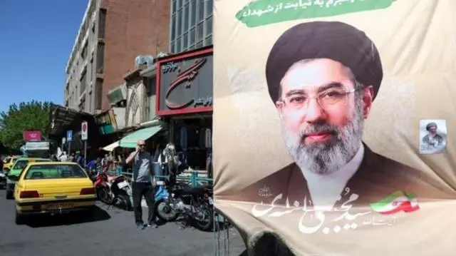صورة المرشد الأعلى الإيراني مجتبى الخامنئي في شارع تظهر فيه سيارات أجرة ومارة