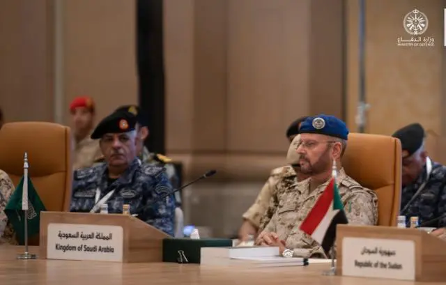 مسؤولون عسكريون يجلسون حول طاولة اجتماع، وأمامهم علما السعودية والسودان، خلال اجتماع بشأن التحالف البحري الدفاعي بقيادة السعودية
